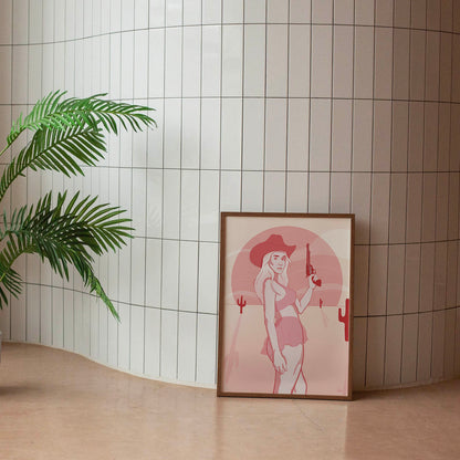 A framed poster depicting a digital drawing of a pink cowgirl in the desert, placed against a tiled wall.
