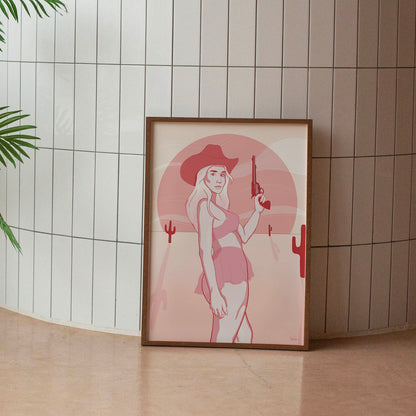 A framed poster depicting a digital drawing of a pink cowgirl in the desert, placed against a tiled wall.